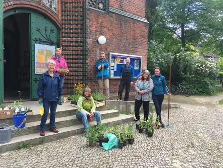 Mitglieder der Umweltgruppe mit Pflanzen und Gartengeräten vor der Petruskirche
